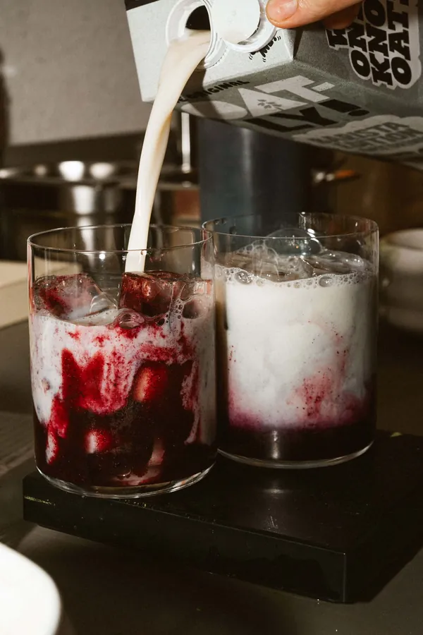 Lait d'avoine versé sur deux boissons glacées aux fruits rouges