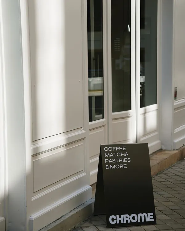 Chevalet Chrome « Coffee, matcha, pastries & more » devant l'entrée du café