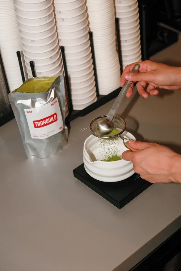 Matcha tamisé dans un bol devant un sachet de matcha Tranquilo